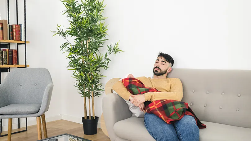 An image of a young man sleeping on sofa with a baby.