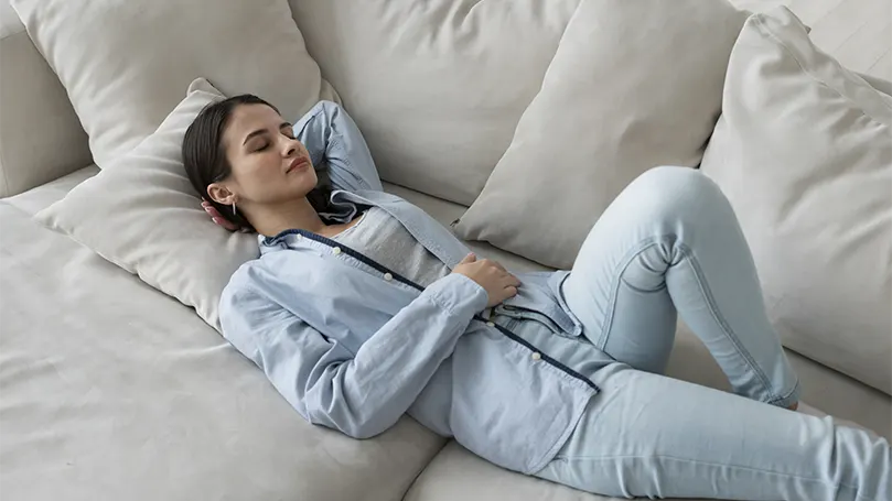 An image of a young woman laying on a couch comfortably