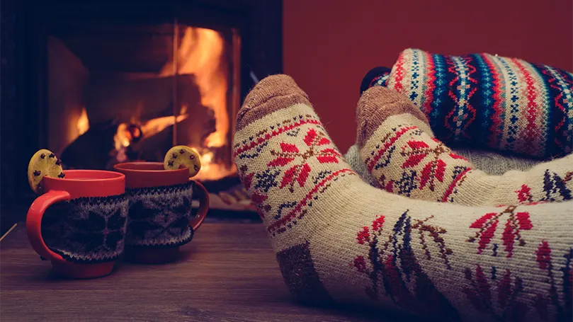 An image of socks on legs next to fireplace.