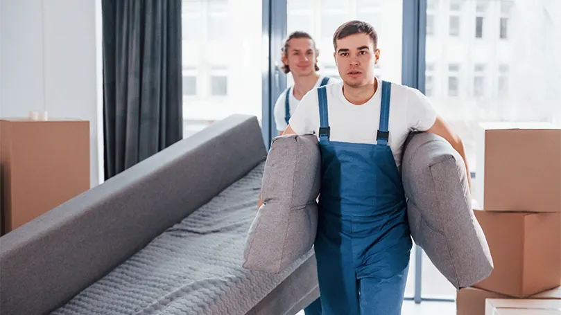An image of two guys from a professional company carrying a bed.