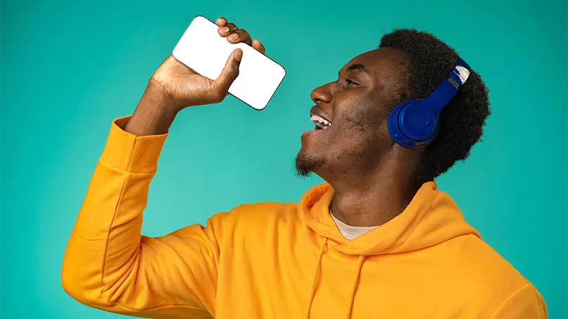 An image of a man listening to music and pretending that his phone is a microphone