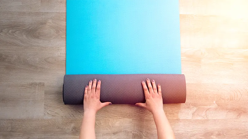 An image of female hands roll a mattress.