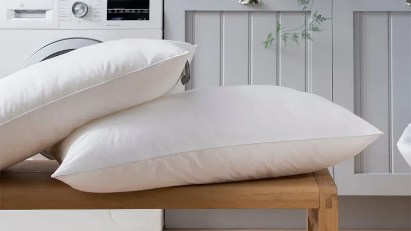 An image of 2 Spundown pillows by the Fine Bedding on stool.