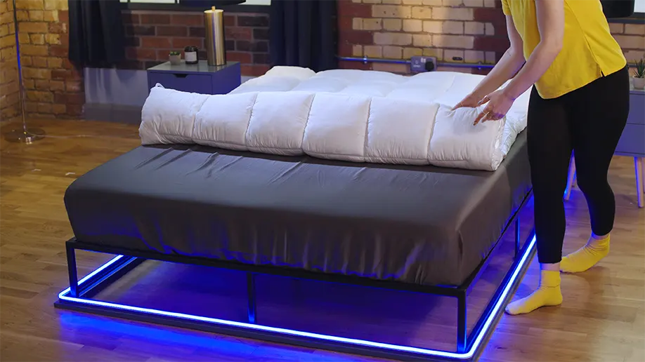 our reviewer unrolling the Silentnight Deep Sleep mattress topper on a bed