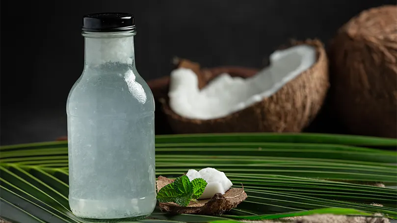 An image of a bottle of coconut water in front of a broken coconut