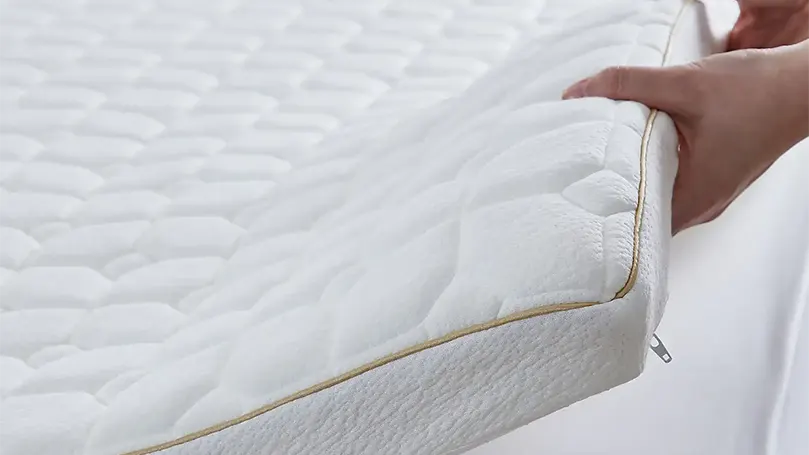 An image of a man holding Dorma Tence mattress topper.