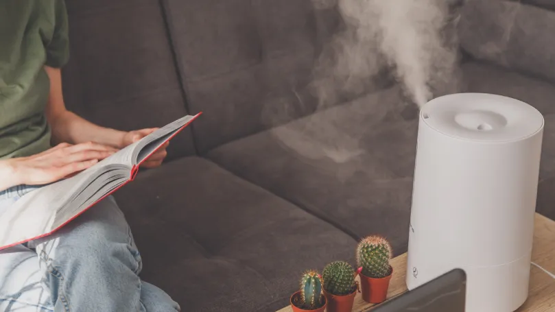 a woman reading a book while using the best humidifier uk