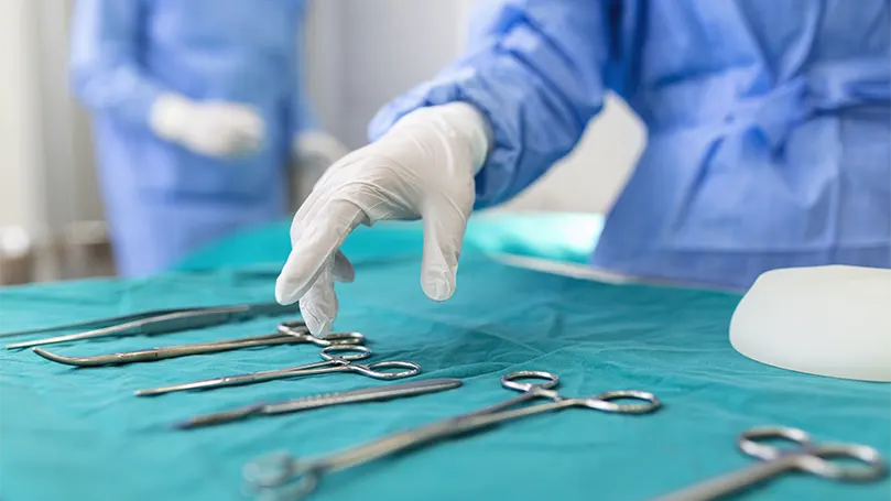 An image of a nurse taking a surgical instrument.