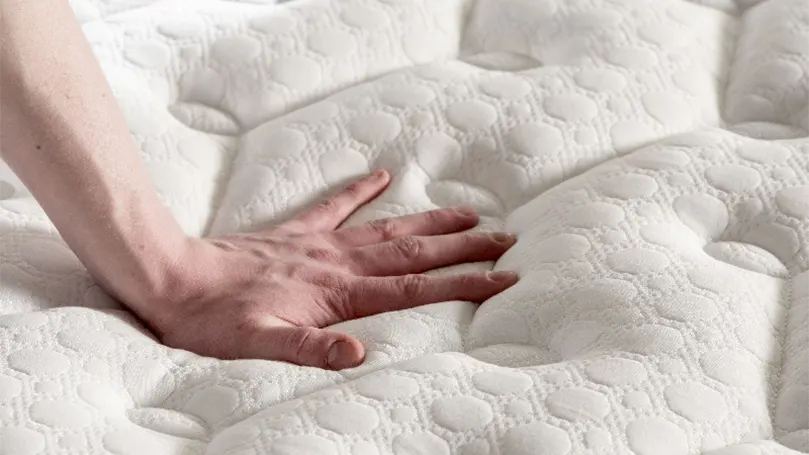 An image of a hand pressing the top of King Arthur mattress.