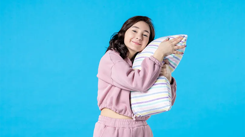 An image of a young woman squeezing a pillow with her hands.