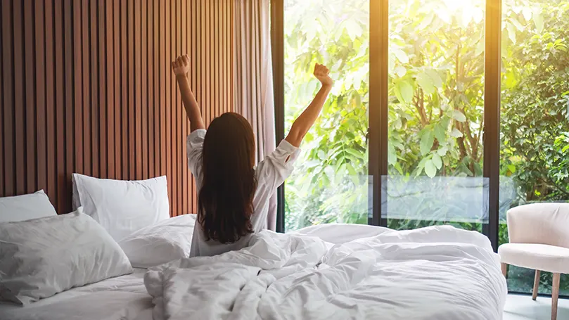 A woman waking up refreshed using bamboo bedding