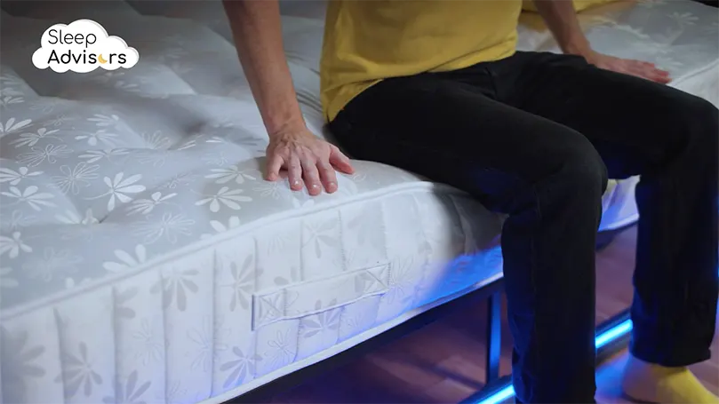 An image of a The Sleep Advisors presenter sitting on the Spare Room Ortho mattress