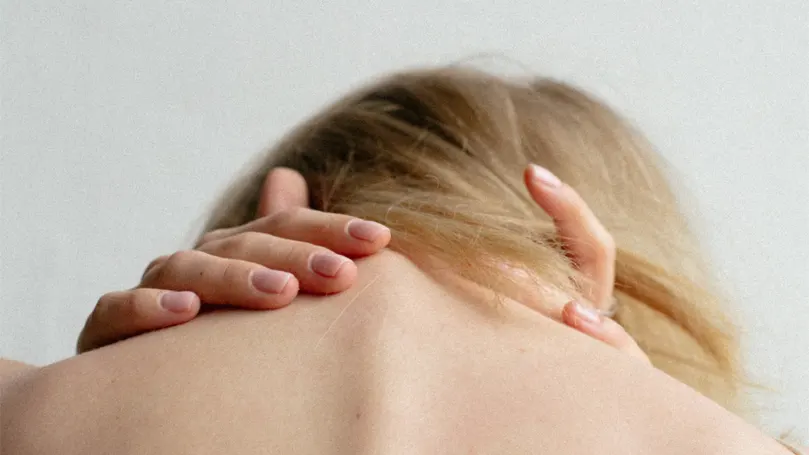 An image of a woman holding the back of her neck due to anxiety and stress