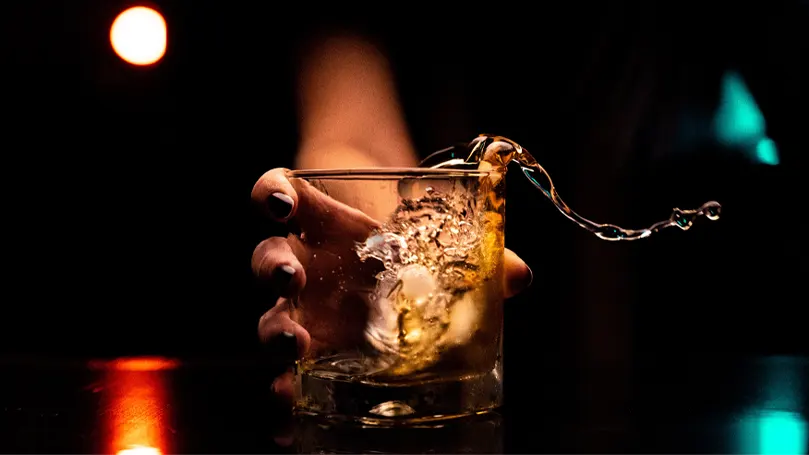 An image of a person holding a glass of alcohol