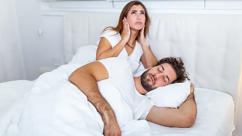 A woman being woken up by a man who is snoring.