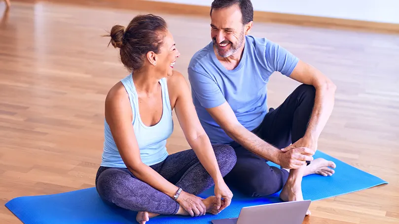 An image of two people taking a rest on a yoga mat after working out and being active