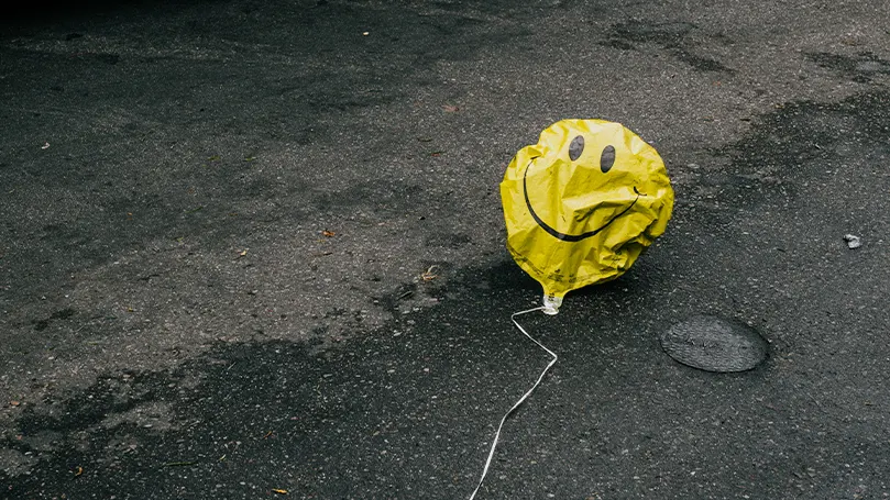 An image of a deflated balloon with a smiley on it