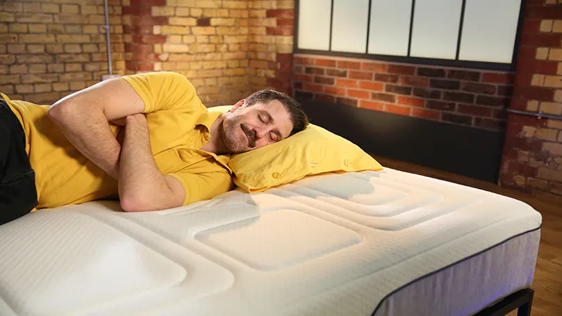 An image of a man laying down on OTTY Pure+ Hybrid Bamboo & Charcoal mattress.