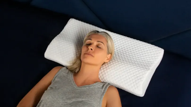 An image of a woman laying on The Original Groove Pillow