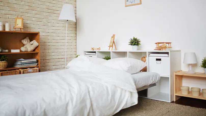 An image of a neat cosy bedroom with a made bed in the middle