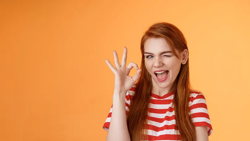 An image of a woman winking and showing an 'ok' sign with her hand.