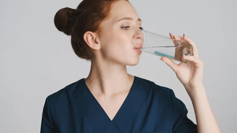 A woman drinking water - one of the top home remedies for hangover.
