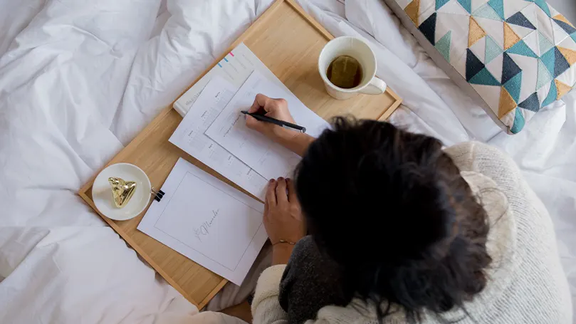 An image of a woman using a table tray in bed.