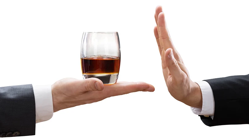 A hand refusing a glass of alcohol