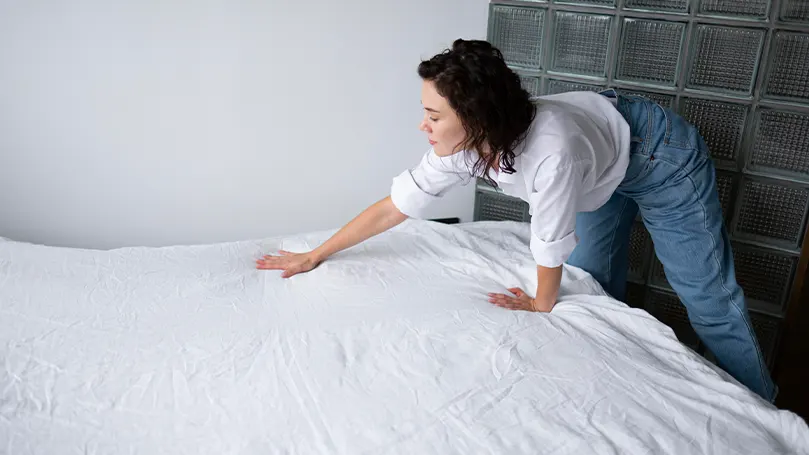 An image of a woman making her bed.