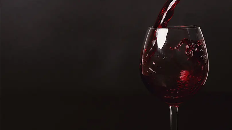 An image of red wine being poured into a glass.