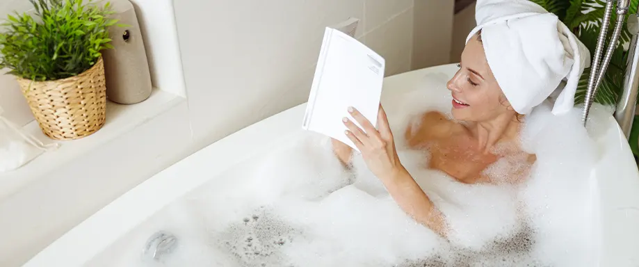 Woman reading book in bathtub