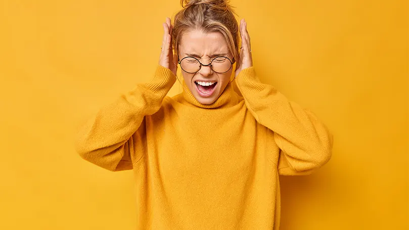 An image of a woman having a panic attack and holding her head with her hands