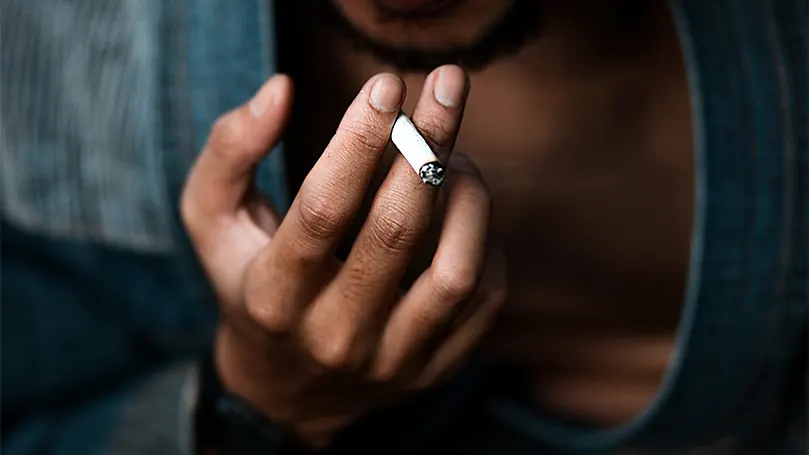 An image of a person holding a cigarette.