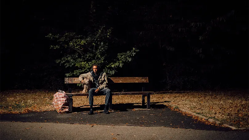 An image of a person sitting on a bench at night