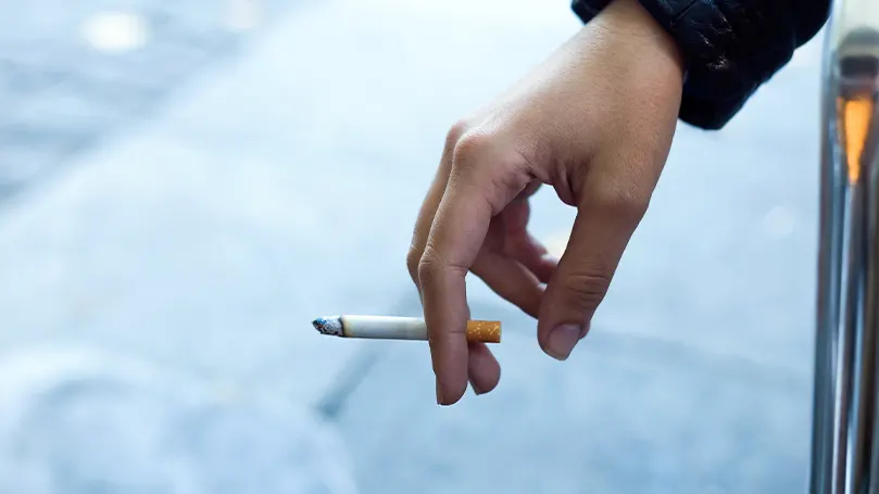 An image of a persons hand holding a cigarette.