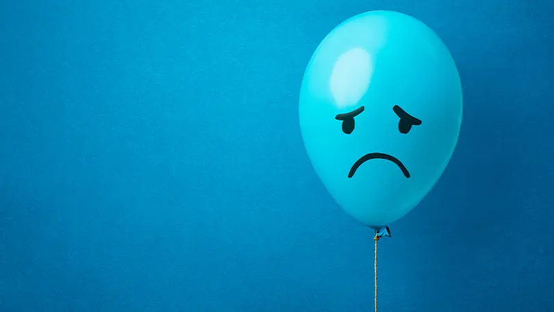 An image of a blue balloon with a sad face drawn on it