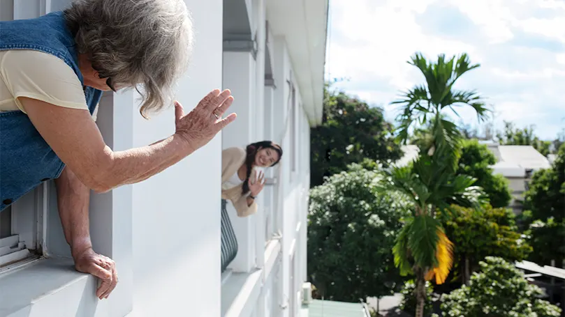 An image of a woman waving at her neighbour
