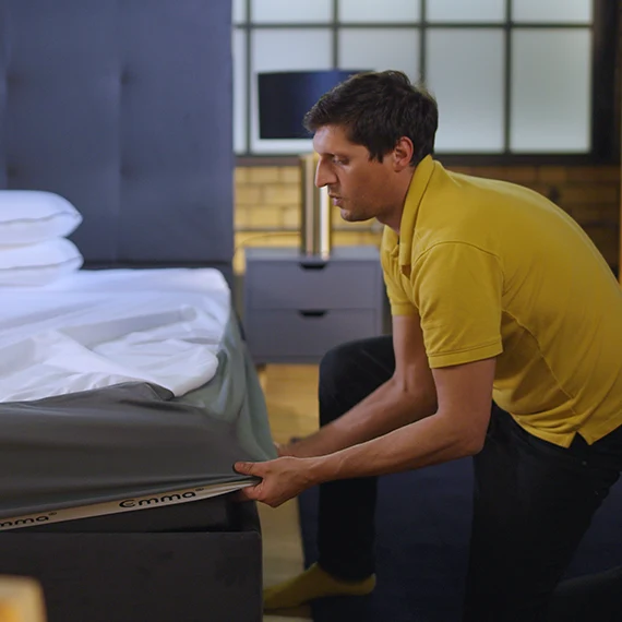 our reviewer putting a Emma Mattress Protector over a mattress