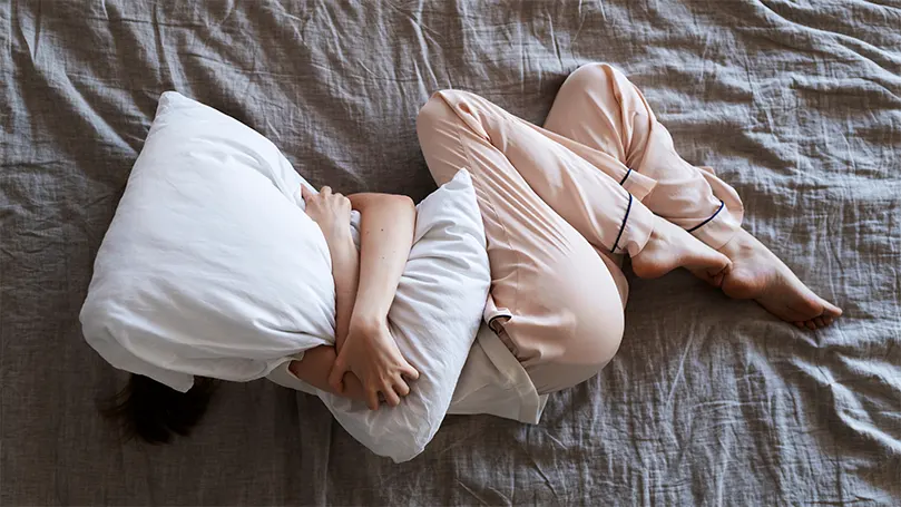 An anxious person hugging their pillow and trying to fall asleep