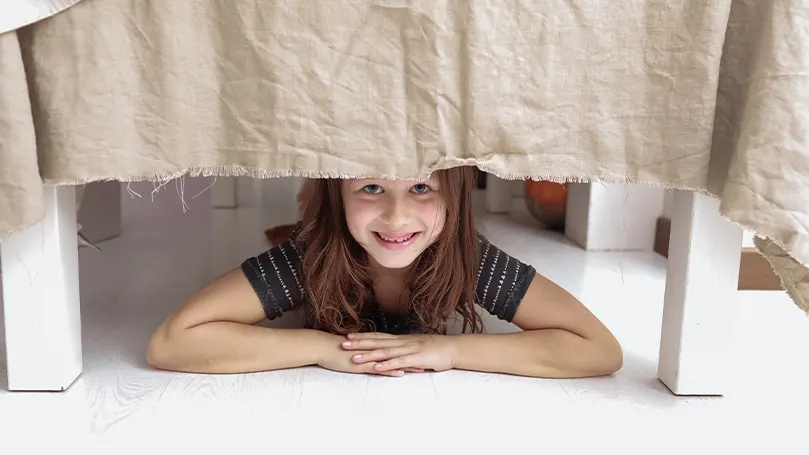 An image of a child underneath a chair fort