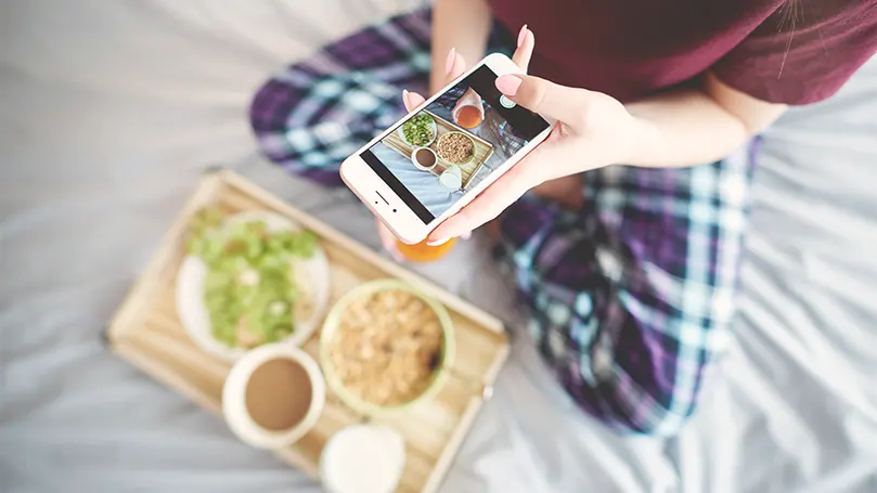 An image of a person eating on bed and taking picture of it.
