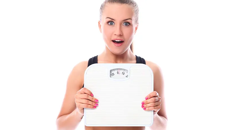 An image of a woman holding up a scale in front of her