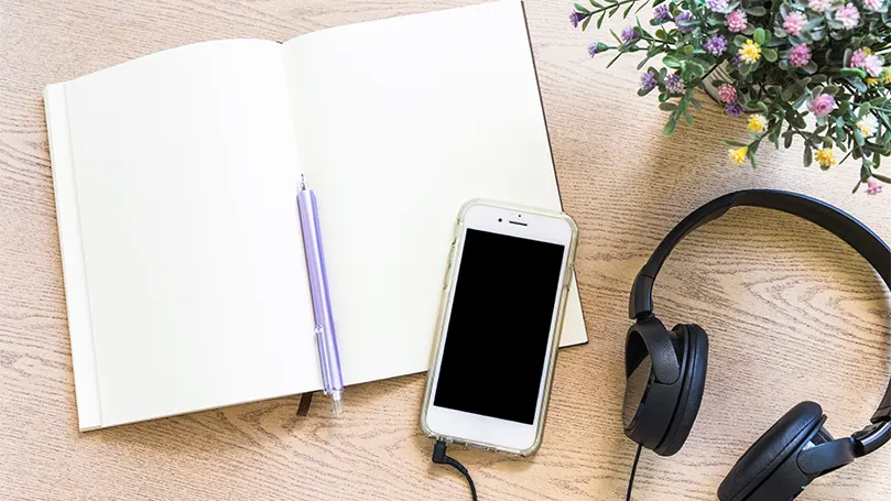 An image of a notebook and a phone on a desk.