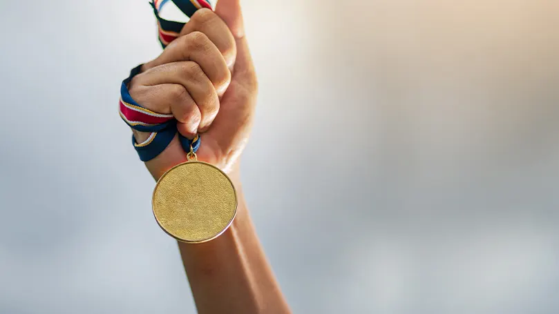 An image of a hand holding a gold medal