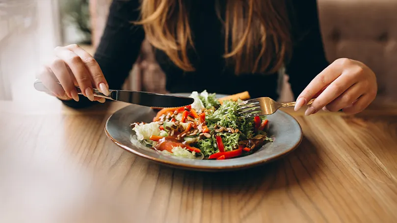 a woman sitting at the able and eating a healthy meal