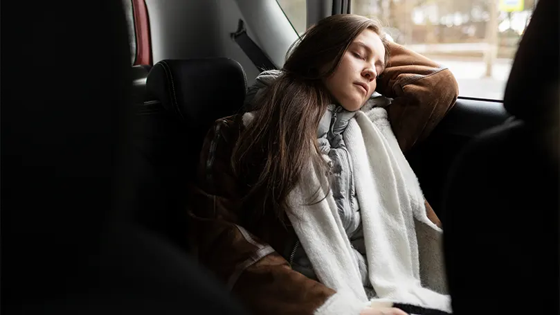 An image of a woman sleeping in her car