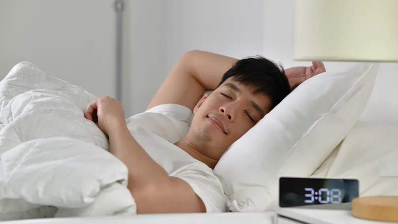 A young Asian man sleeping in bed