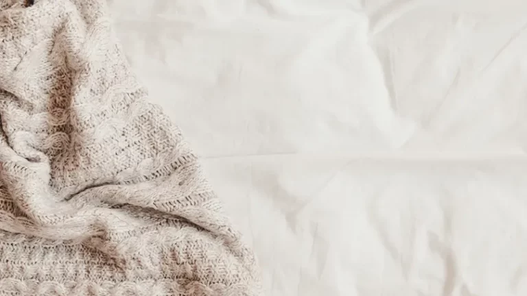 An image of a blanket placed on bed sheets