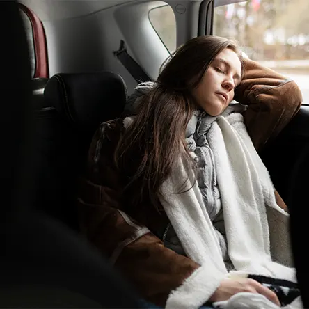 An image of a woman sleeping in her car.