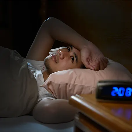 An image of a man in bed awake and looking at the ceiling